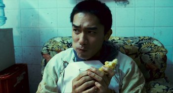 Movie still from “Happy Together” (1997), directed by Kar-Wai Wong – A man sitting on a couch eating a sandwich; Close Up shot, Over the shoulder angle
