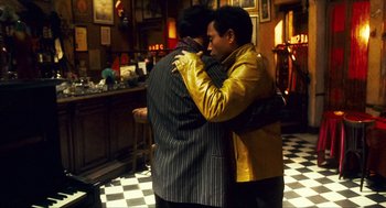 Movie still from “Happy Together” (1997), directed by Kar-Wai Wong – A couple of men standing next to each other in a room; Medium shot, Over the shoulder angle