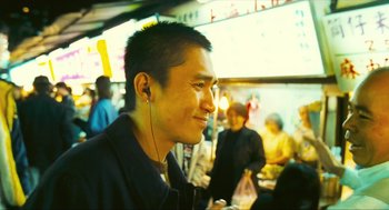Movie still from “Happy Together” (1997), directed by Kar-Wai Wong – A young man with headphones is smiling for the camera; Close Up shot, Over the shoulder angle