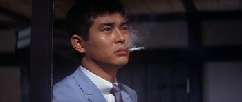 A man in a suit and tie smoking a cigarette