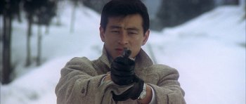 A man holding a gun while wearing gloves and a jacket