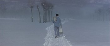 A man in a blue suit is walking in the snow