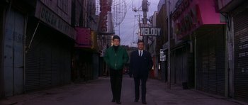 Two men standing on a city street in front of a building