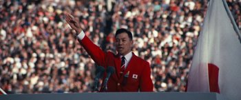 A man in a red jacket waves to the crowd