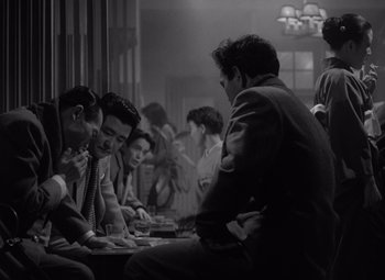 A black and white photo of a group of men sitting at a table