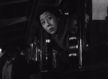 A black - and - white photo of a man looking out a window
