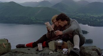 Movie still from “Tommy” (1975), directed by Ken Russell – A man and a woman sitting next to each other on top of a hill; Wide shot, High angle