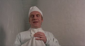 Movie still from “Tommy” (1975), directed by Ken Russell – A man wearing a white hat and a white robe; Close Up shot, Low angle