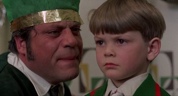 Movie still from “Tommy” (1975), directed by Ken Russell – A man and a boy wearing green and gold hats; Close Up shot, Over the shoulder angle
