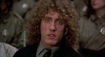 Movie still from “Tommy” (1975), directed by Ken Russell – A person wearing a suit and tie; Close Up shot, Low angle