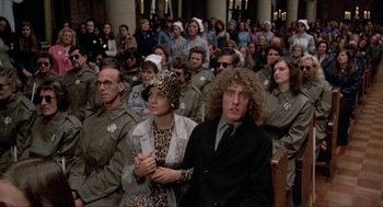Movie still from “Tommy” (1975), directed by Ken Russell – A group of people sitting in front of each other; Medium shot, High angle