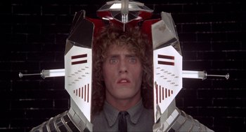 Movie still from “Tommy” (1975), directed by Ken Russell – A man in a suit and tie with a weird face; Close Up shot, Low angle