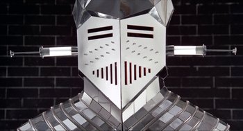 Movie still from “Tommy” (1975), directed by Ken Russell – View of the face of a metal suit of armor; Close Up shot, Low angle