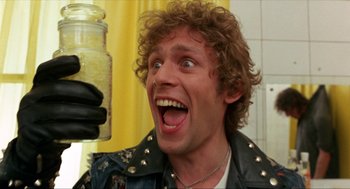 Movie still from “Tommy” (1975), directed by Ken Russell – A man holding a jar of food in his hand; Close Up shot, Low angle