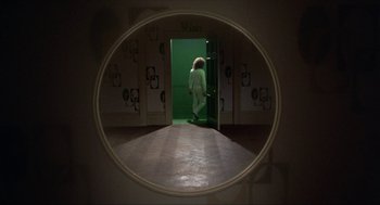 Movie still from “Tommy” (1975), directed by Ken Russell – A person is standing in a doorway in a bathroom; Wide shot, High angle