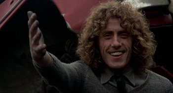 Movie still from “Tommy” (1975), directed by Ken Russell – A person with curly hair holding an umbrella; Close Up shot, Low angle