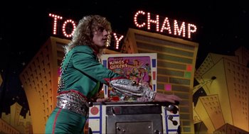 Movie still from “Tommy” (1975), directed by Ken Russell – A man dressed as a rock star playing a video game; Medium shot, Low angle