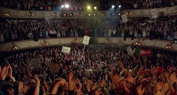 Movie still from “Tommy” (1975), directed by Ken Russell – A crowd of people in an auditorium with signs; Extreme Wide shot, High angle