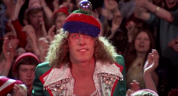 Movie still from “Tommy” (1975), directed by Ken Russell – A man in a colorful hat and a green jacket; Close Up shot, Low angle