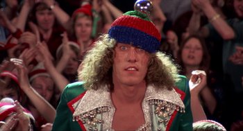 Movie still from “Tommy” (1975), directed by Ken Russell – A man in a green jacket wearing a red and blue hat; Close Up shot, Low angle