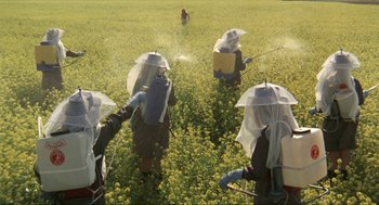 Movie still from “Tommy” (1975), directed by Ken Russell – A group of people in the middle of a field spraying water; Wide shot, High angle