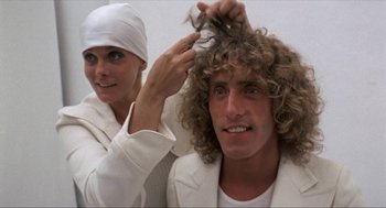 Movie still from “Tommy” (1975), directed by Ken Russell – A man with long blonde hair is getting his hair combed by a woman; Close Up shot, Low angle