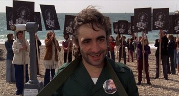 Movie still from “Tommy” (1975), directed by Ken Russell – A man in a green jacket and a button on his shirt; Medium shot, Low angle