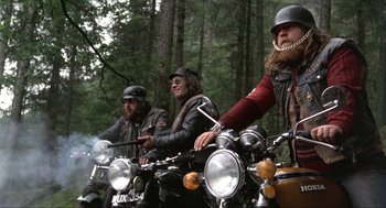 Movie still from “Tommy” (1975), directed by Ken Russell – A group of men riding motorcycles in the woods; Wide shot, Low angle