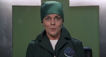 Movie still from “Tommy” (1975), directed by Ken Russell – A woman wearing a green hat and a green jacket; Close Up shot, Low angle