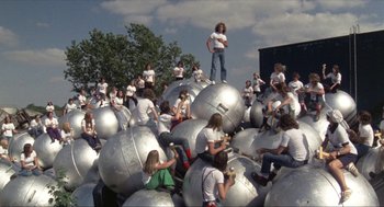 Movie still from “Tommy” (1975), directed by Ken Russell – A group of people sitting on top of silver balls; Wide shot, High angle