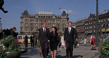 Movie still from “Topaz” (1969), directed by Alfred Hitchcock – A group of people in suits walking on the street; Wide shot, Low angle