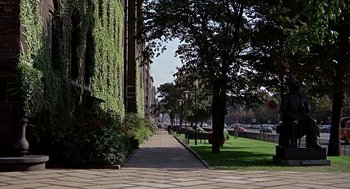 Movie still from “Topaz” (1969), directed by Alfred Hitchcock – A sidewalk lined with trees and bushes near a building; Extreme Wide shot, High angle