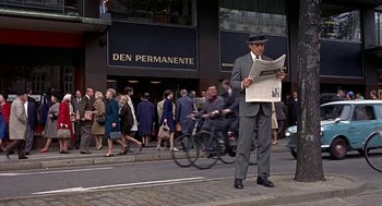 Movie still from “Topaz” (1969), directed by Alfred Hitchcock – A man reading a newspaper while standing on the side of the street; Wide shot, Low angle