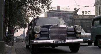 Movie still from “Topaz” (1969), directed by Alfred Hitchcock – An old black car driving down the street; Wide shot, Low angle