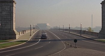Movie still from “Topaz” (1969), directed by Alfred Hitchcock – A car driving down a street with a bridge in the background; Extreme Wide shot, High angle