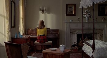 Movie still from “Topaz” (1969), directed by Alfred Hitchcock – A woman sitting at a piano in front of a fireplace; Wide shot, High angle