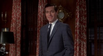 Movie still from “Topaz” (1969), directed by Alfred Hitchcock – A man wearing a suit and tie standing in front of a mirror; Medium shot, Low angle