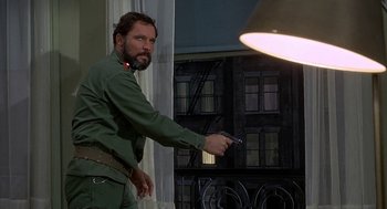 Movie still from “Topaz” (1969), directed by Alfred Hitchcock – A man holding a gun while standing in front of a window; Medium shot, Low angle