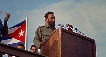 Movie still from “Topaz” (1969), directed by Alfred Hitchcock – A man standing at a podium speaking to a crowd; Medium shot, Low angle