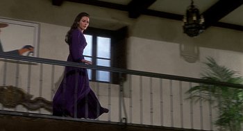 Movie still from “Topaz” (1969), directed by Alfred Hitchcock – A woman in a purple dress walking down stairs; Wide shot, Low angle