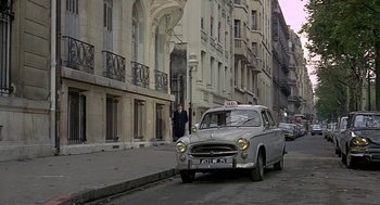 Movie still from “Topaz” (1969), directed by Alfred Hitchcock – A taxi cab is driving down the street in front of a tall building; Wide shot, Low angle