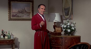 Movie still from “Topaz” (1969), directed by Alfred Hitchcock – A man in a red bathrobe standing in front of a table with a lamp; Medium shot, Low angle