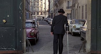 Movie still from “Topaz” (1969), directed by Alfred Hitchcock – A man in a suit and hat walking down the street; Wide shot, High angle