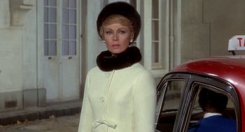 Movie still from “Topaz” (1969), directed by Alfred Hitchcock – A woman wearing a white coat and a fur hat; Medium shot, Low angle