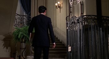Movie still from “Topaz” (1969), directed by Alfred Hitchcock – A man in a suit walking up a set of stairs; Wide shot, Low angle