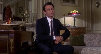 Movie still from “Topaz” (1969), directed by Alfred Hitchcock – A man in a suit sitting in a living room; Medium shot, Low angle