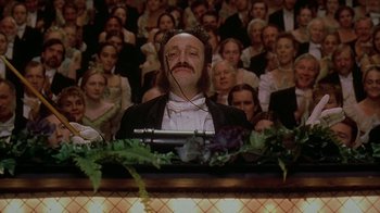 Movie still from “Topsy-Turvy” (1999), directed by Mike Leigh – A man with a beard and a mustache in front of an audience; Medium shot, Low angle