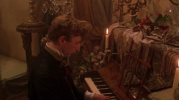 Movie still from “Topsy-Turvy” (1999), directed by Mike Leigh – A man is playing the piano by candlelight; Medium shot, High angle