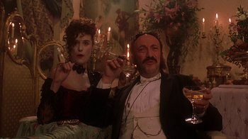 Movie still from “Topsy-Turvy” (1999), directed by Mike Leigh – A man and a woman sitting next to each other in front of candles; Medium shot, Low angle