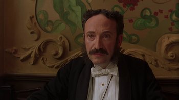 Movie still from “Topsy-Turvy” (1999), directed by Mike Leigh – A man with a mustache wearing a suit and bow tie; Close Up shot, Low angle